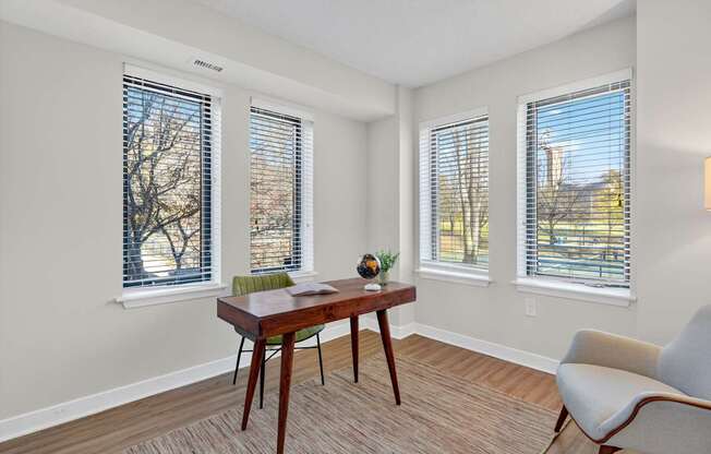 A room with a table, chairs and windows.