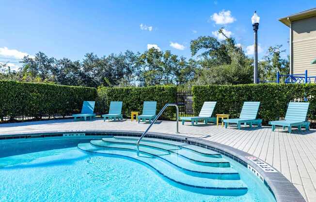 A swimming pool with blue water and lounge chairs.