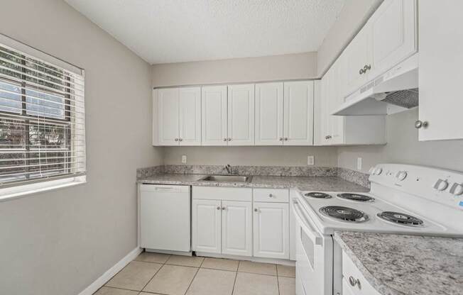 A kitchen with white cabinets and a white stove top oven.