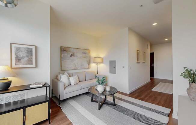 A living room with a white couch, a coffee table, and a lamp.