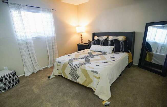 A bedroom with a bed, lamp, and window.