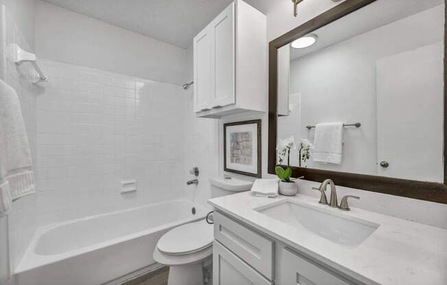 A white bathroom with a toilet, sink, and bathtub.