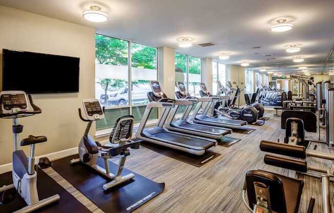 A gym with a variety of equipment including treadmills, stationary bikes, and weight machines.