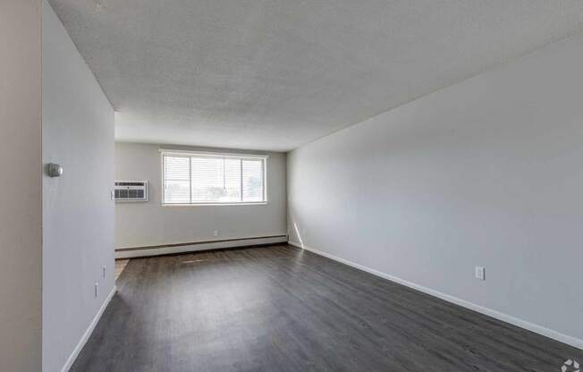 an empty living room with hardwood floors and a window