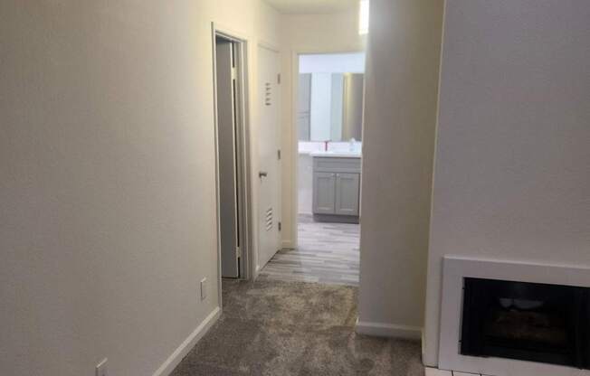 A hallway with a fireplace and a door on the left.