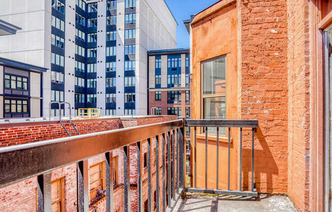 A balcony with a metal railing overlooks a brick building.