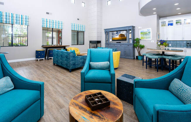 a lounge area with blue chairs and a table with a fireplace