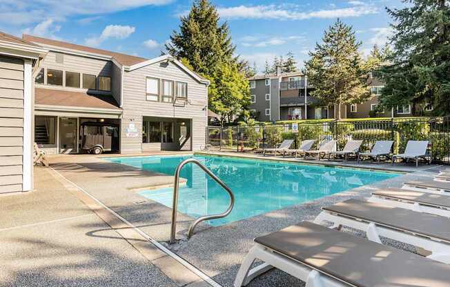 A pool with sun loungers in front of a building.