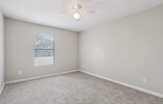 A room with a ceiling fan and carpeted floor.