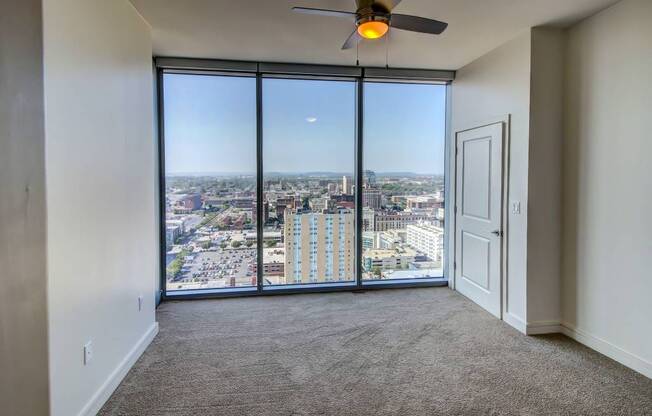 A room with a ceiling fan and a view of the city.