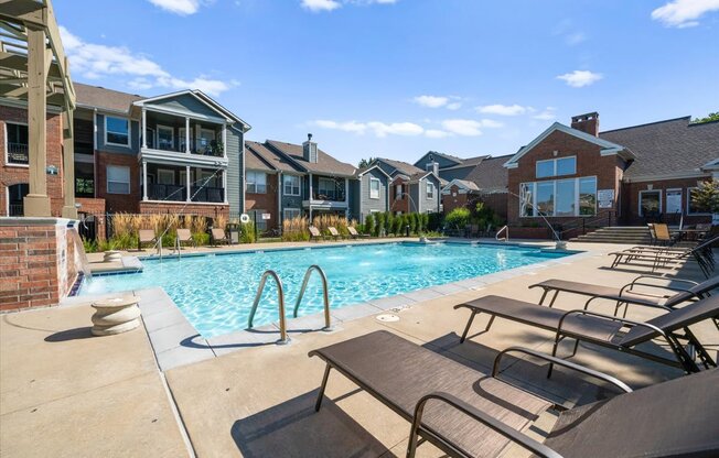 A pool surrounded by lounge chairs and buildings in the background. at Somerset Oaks Apartment Homes, Olathe, KS