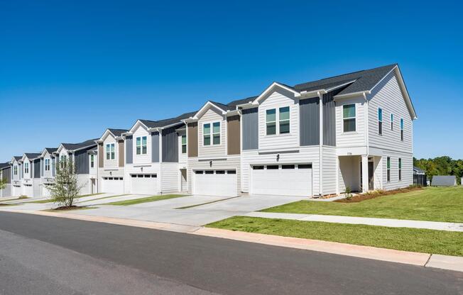 The community features spacious townhomes with private two-car garages, contemporary exterior designs, and thoughtfully planned neighborhood streets that combine low-maintenance living with the comfort of a larger home.
