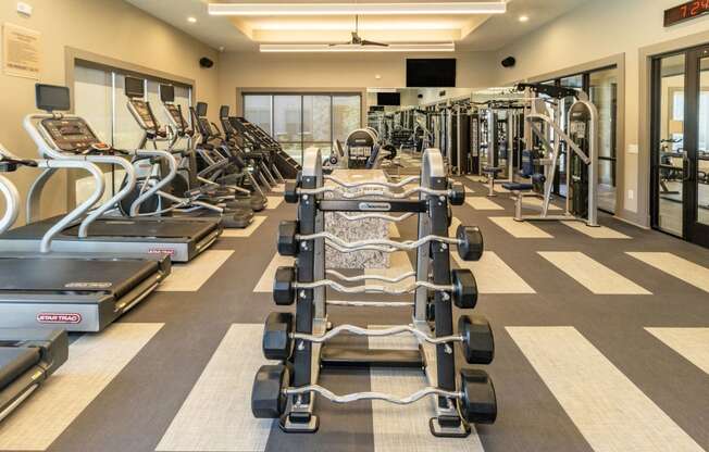 a large fitness room with cardio equipment and weights