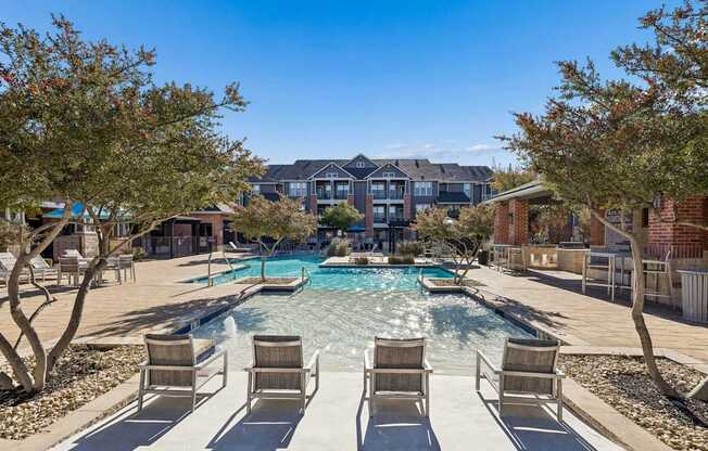A pool surrounded by chairs and trees with a building in the background.