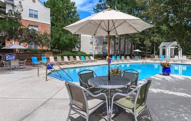 A patio with a table and chairs and a pool.