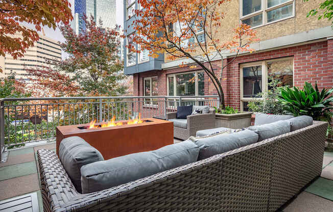 A patio with a fire pit and wicker furniture.
