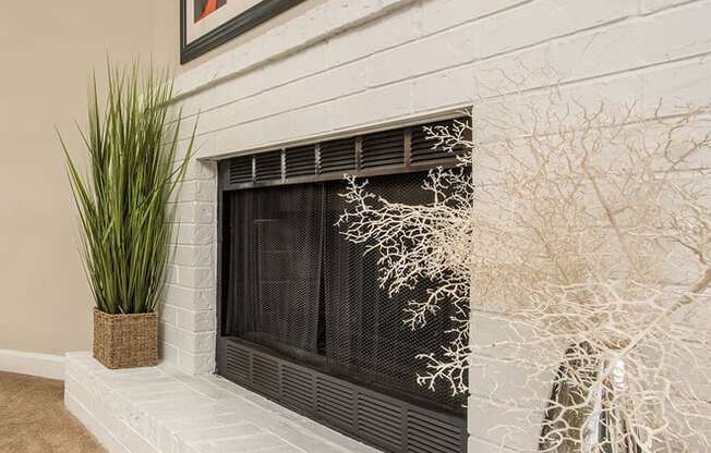 a white brick fireplace with a plant and paintings on the wall at Lodge of Overland Park Apartments, Overland Park , KS