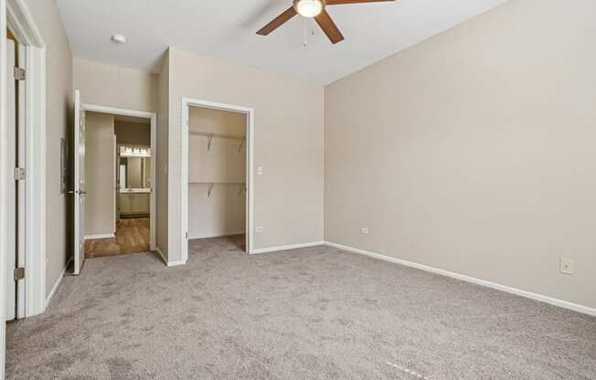 A room with a ceiling fan and two open closets.
