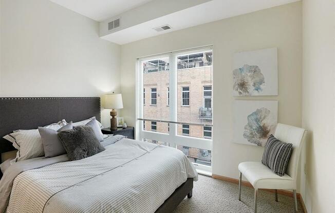 A bedroom with a large bed and a chair by the window.