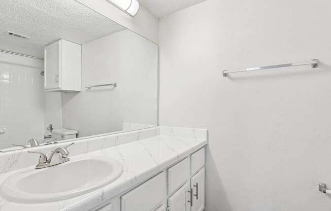 A white bathroom with a sink and a mirror.