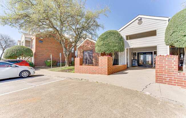 A parking lot in front of a building with a car parked.