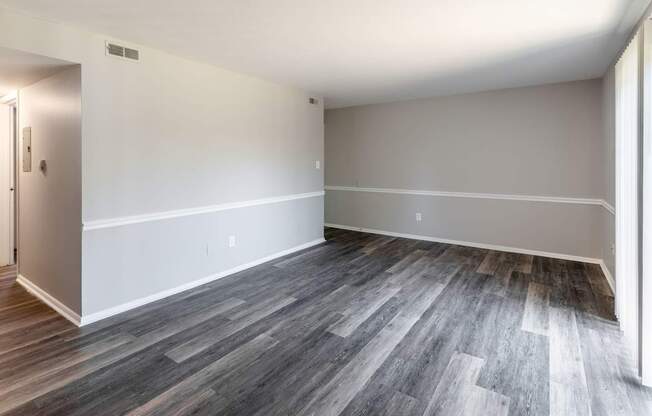an empty living room with wood floors and white walls