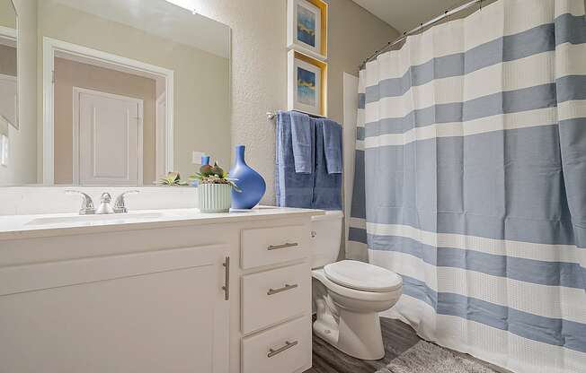 A bathroom with a white sink and a blue and white striped shower curtain at Sterling Point Apartment Homes, Arizona