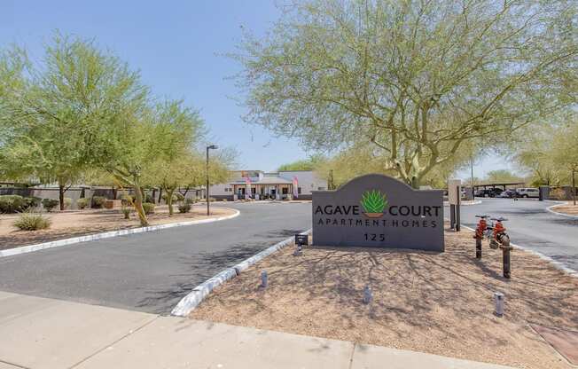 a sign that says agave court apartments with a building in the background