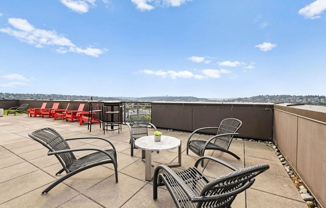 A patio with black metal chairs and tables overlooks a cityscape.