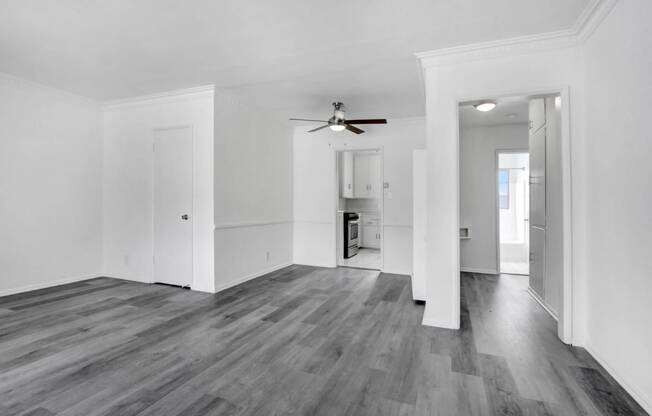 an empty living room with white walls and a ceiling fan