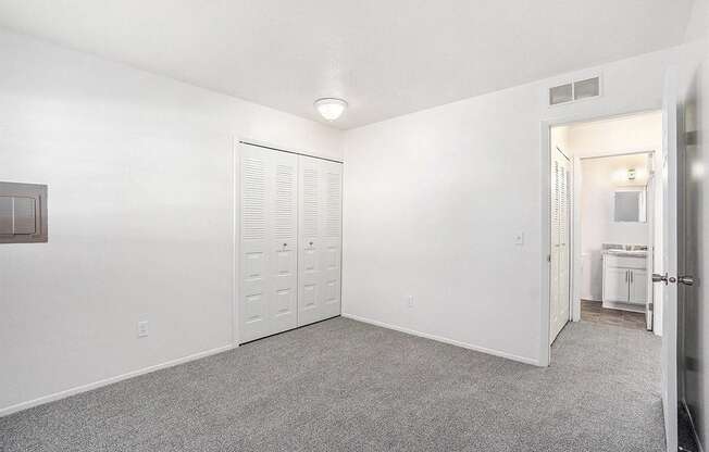 A white room with a grey carpet and a white door.