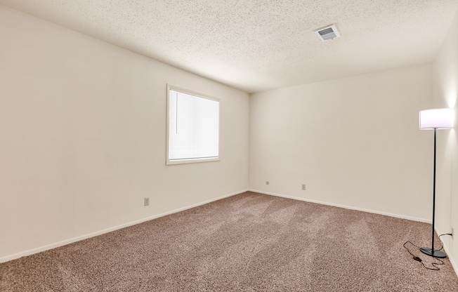 A room with a carpeted floor and a window.