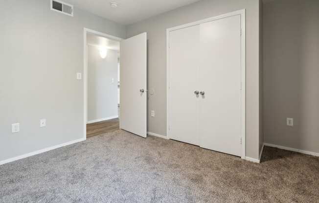 an empty room with white doors and a carpeted floor