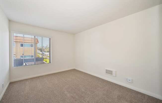 an empty living room with a window and carpet