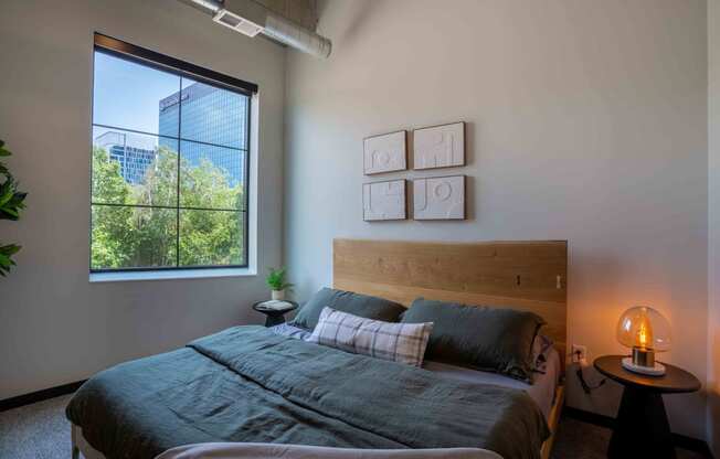 Bloomington, MN Apartments - Carbon31 - Bedroom with Large Window, Wall-to-wall Carpet, Large Bed, and Circular Nightstand