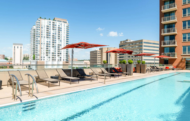 a swimming pool with chairs and umbrellas on top of a building