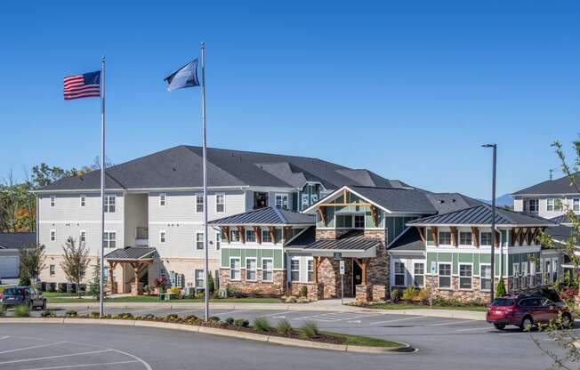 an empty parking lot in front of an apartment building with two flags flying