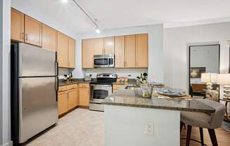 A kitchen with a refrigerator, microwave, oven, and bar stools.