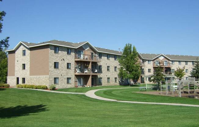 an exterior view of an apartment building with a green yard