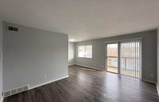 an empty living room with wood floors and a sliding glass door