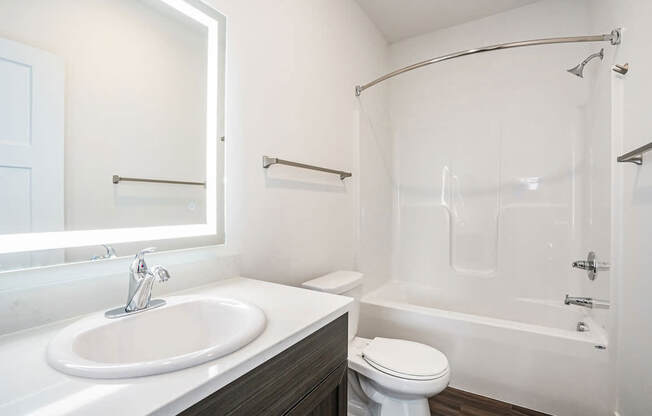 A bathroom with a bathtub/shower combination and a lighted mirror at Meadowbrooke Apartment Homes in Kentwood, MI 49512