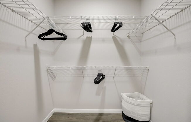A white closet with clothes hanging on hangers.