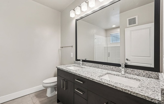 A moderne bathroom with granite countertops and stand up frameless glass door shower.