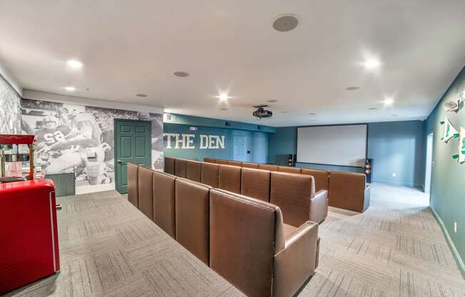 the den screening room with leather seating and a projector screen