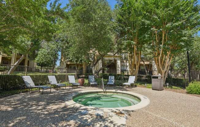 a small fountain with chairs around it in a courtyard with trees