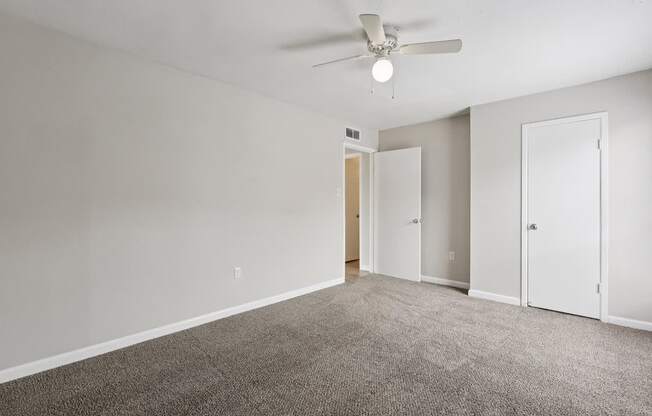 A room with a ceiling fan and carpeted floor.