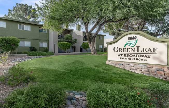 A sign for Green Leaf Apartments is in front of a building.