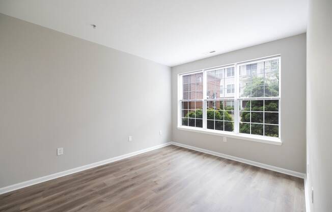 an empty room with wood floors and a large window