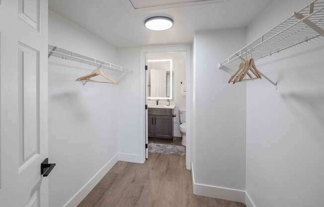 a closet in a bedroom with white walls and wood floors