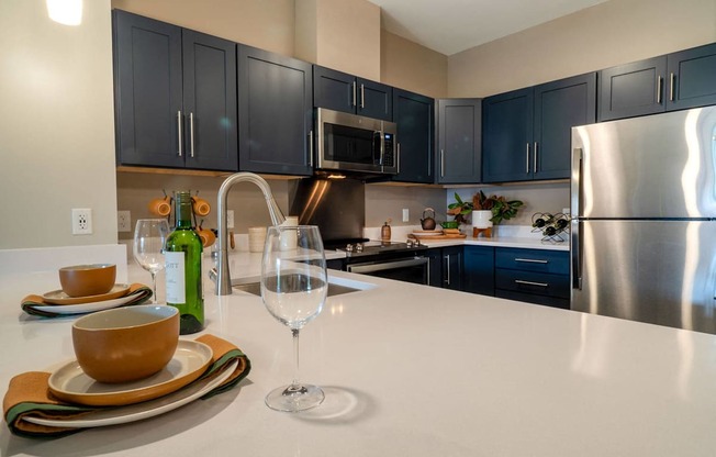 A modern kitchen with stainless steel appliances, quartz countertops, and dark cabinetry.